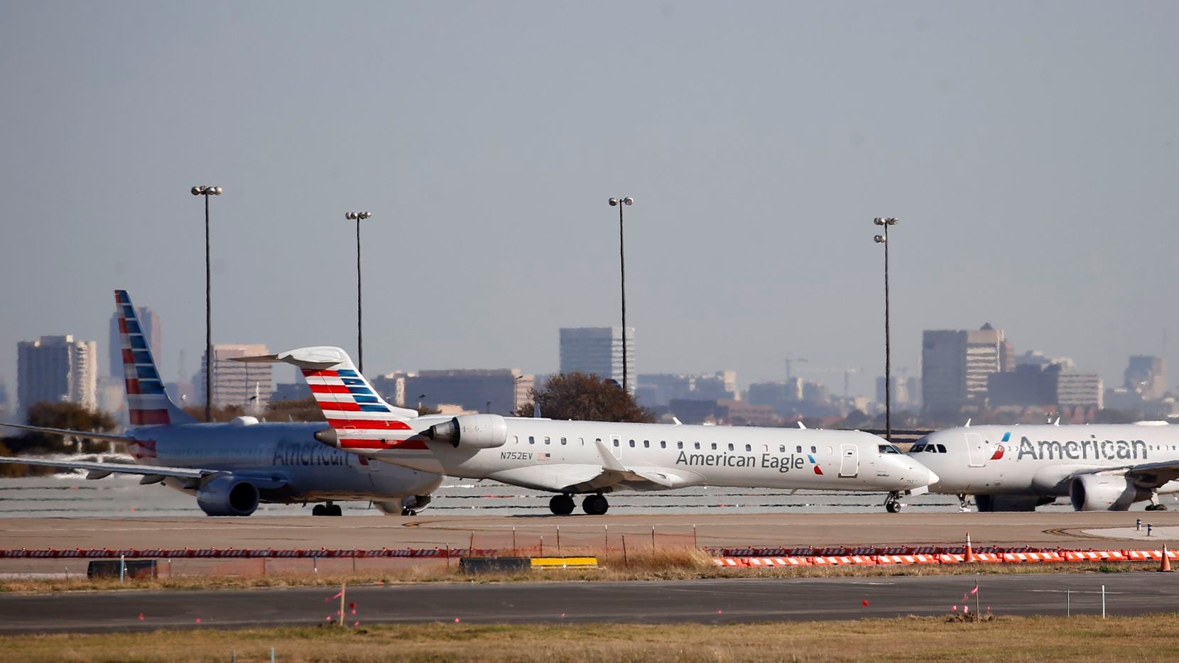 An American Eagle and American Airlines planes make their way toward the runway before...
