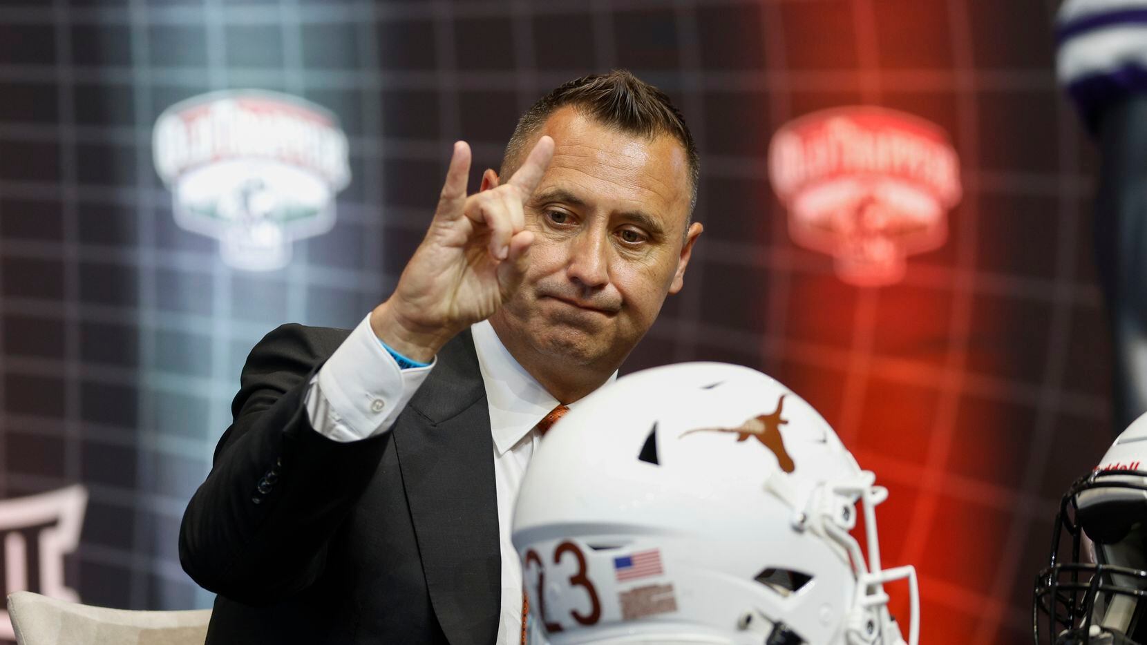 Texas head coach Steve Sarkisian holds up hook’ em horns during the Big 12 Media Days at...