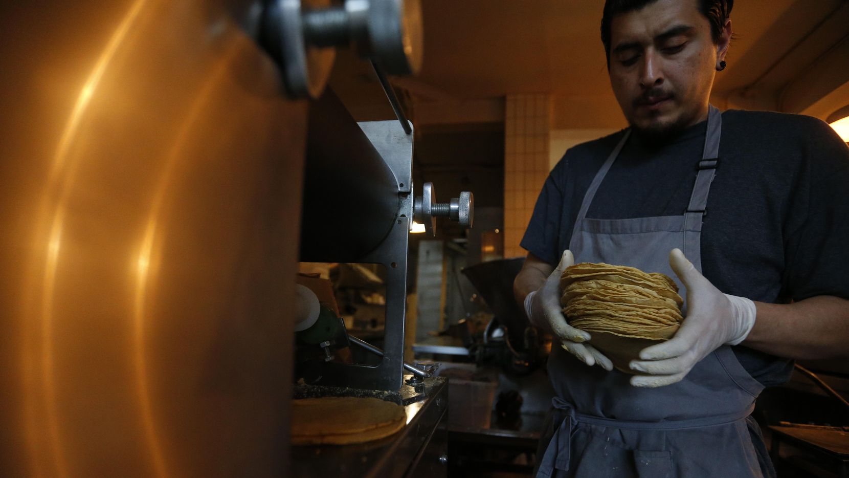 Jesús Saldivar toma tortillas recien salidas de la máquina del Molino El Pujol, en la Ciudad...
