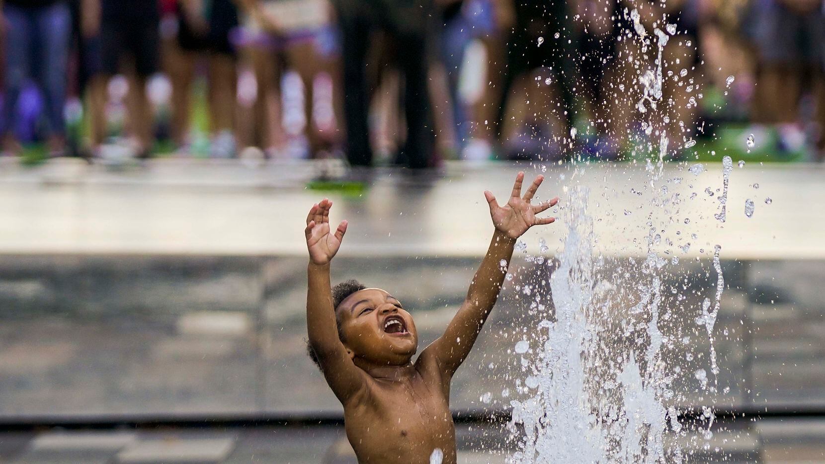 Massiah Webb, 4, plays in a fountain as Dallas ISD trustee Maxie Johnson addresses a rally for Juneteenth in the background at Klyde Warren Park in 2020 in Dallas.