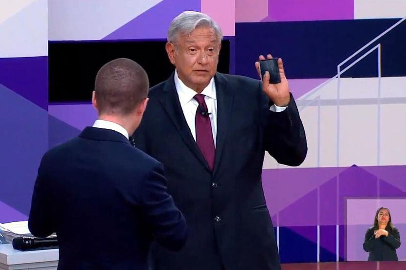El candidado Andrés Manuel López Obrador levanta su cartera cuando se le acerca el candidato...