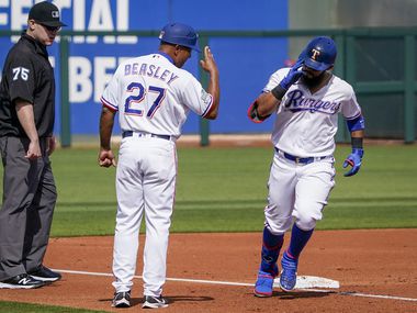 Texas Rangers third base coach Tony Beasley salutes second baseman Rougned Odor as he rounds the bases after hitting a grand slam home run during the first inning of a spring training game against the Chicago Cubs at Surprise Stadium on Thursday, Feb. 27, 2020, in Surprise, Ariz. 
