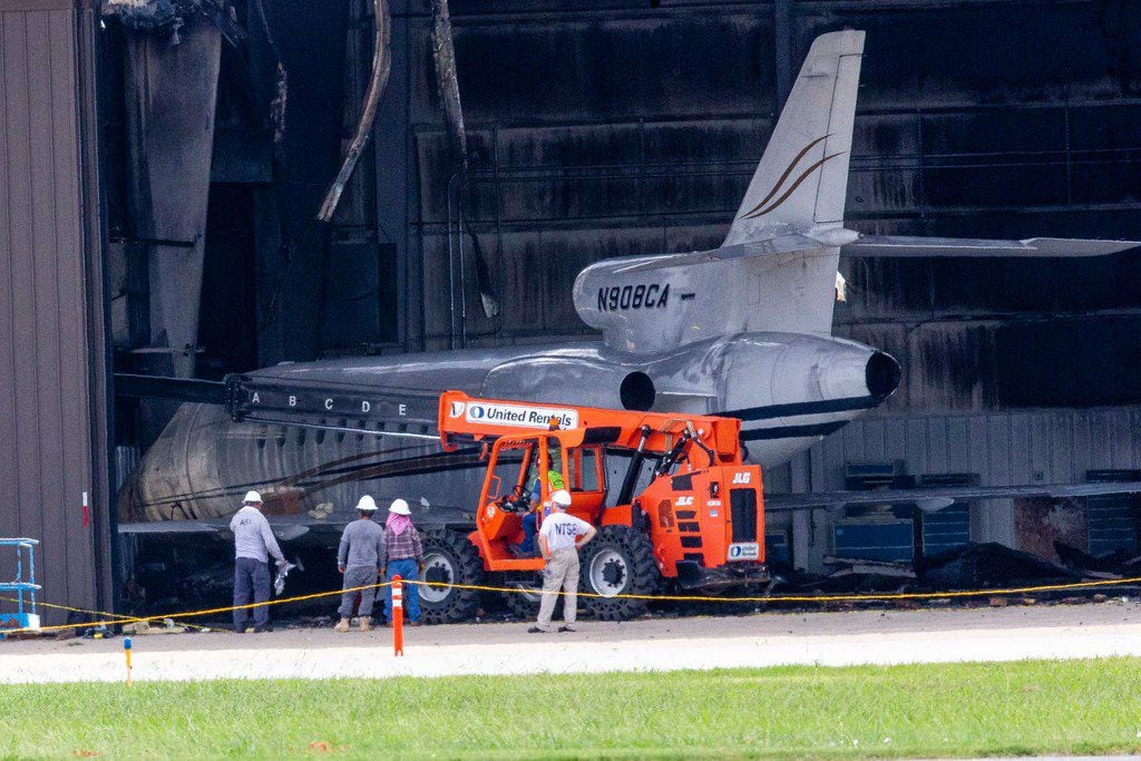 NTSB and others inspect a damaged and burned hangar where a plane crashed a day earlier at...