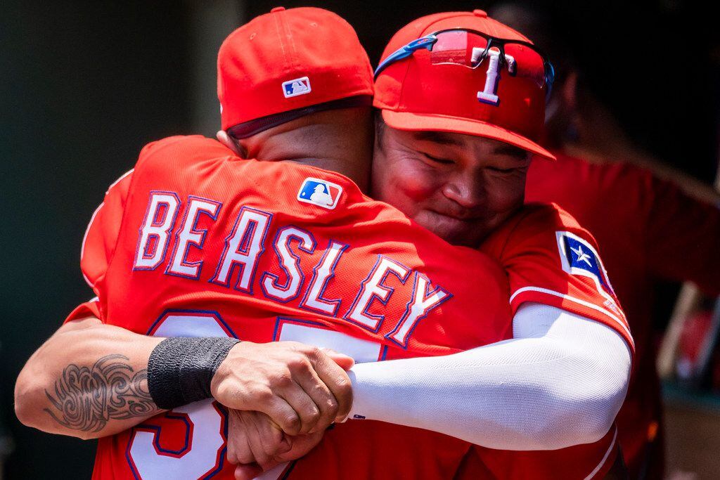 Texas Rangers outfielder Shin-Soo Choo hugs third base coach Tony Beasley in the dugout...