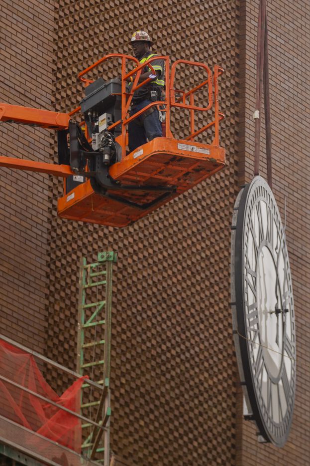 A worker from MEI Rigging & Crating works to install a 12-foot glass clock on the Grapevine...
