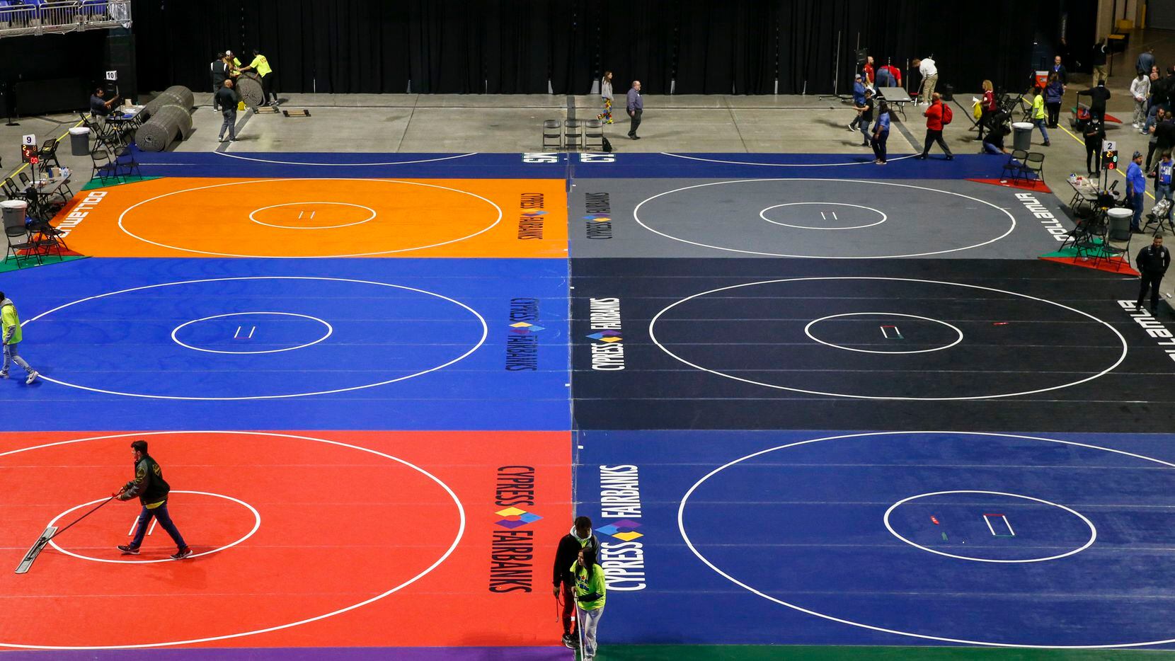 Workers clean the mats during a break at the UIL State Wrestling tournament at the Berry...