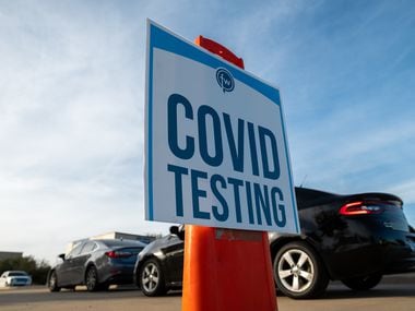 Signage is on display as motorists wait for a COVID-19 test in the parking lot of Friendship-West Baptist Church in south Dallas, on Jan. 6, 2022. The testing site is partnering with Zoom Medical Testing and Sunshine Labs to host the free rapid testing site.