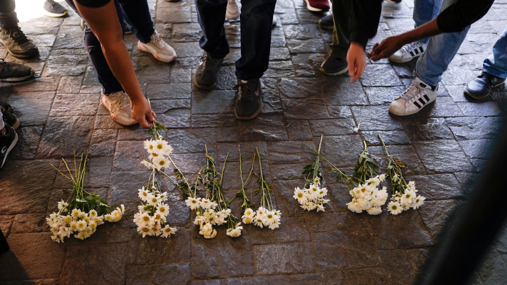 People leave flowers during a protest against a recent fire at a Mexican immigration...