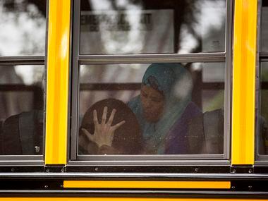 Kara Zartler covers her ears with her hands as the school bus pulls up in front of her...