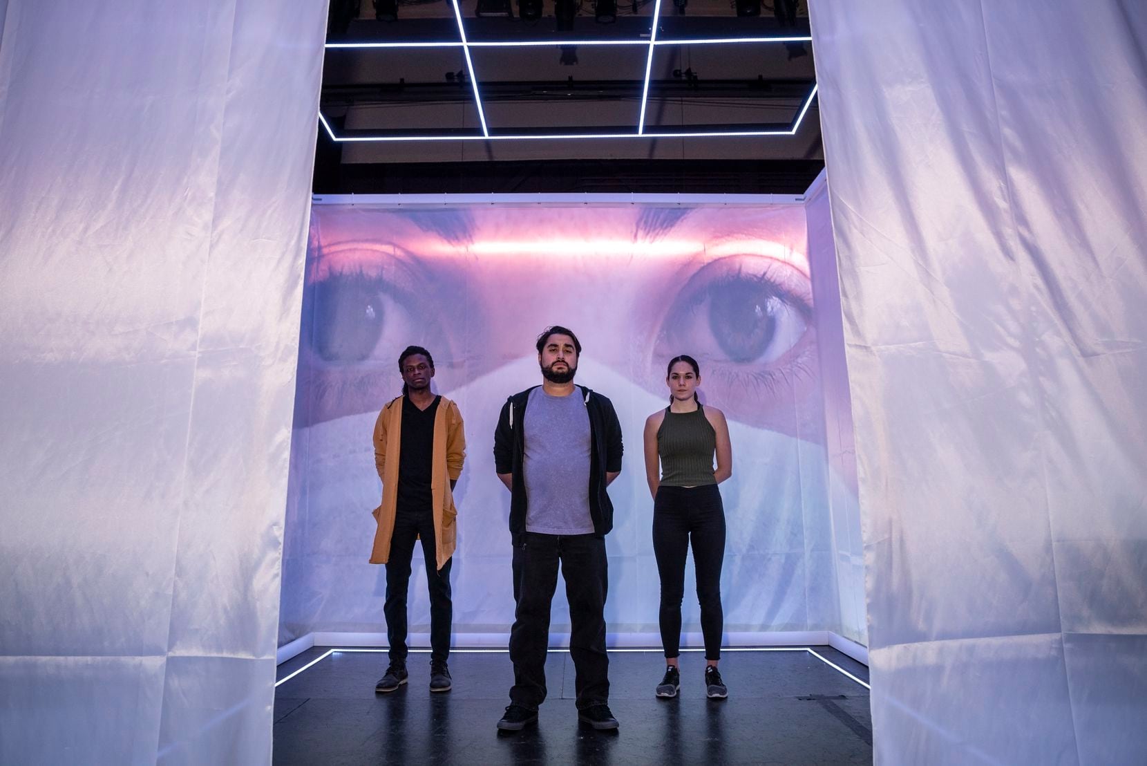 Writer-director Ruben Carrazana (center) composer-musician Nigel Newton (left) and choreographer-dancer Emily Bernet (right) pose for a portrait inside "The Cube" at the Latino Cultural Center. Conceived by Carrazana and set designer Jeffery Bryant Moffitt, the sold-out production is that rare beast amid the pandemic: live theater for an in-person audience.
