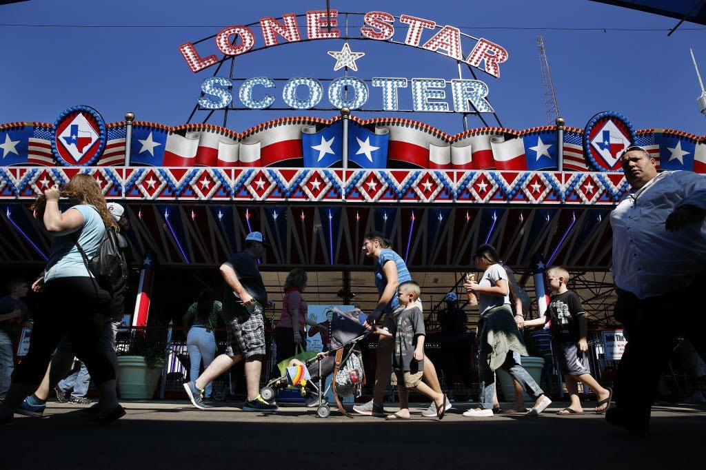 Fairgoers pass the Lone Star Scooters bumper cars ride along the Midway at the State Fair of Texas  on Friday, October 16, 2015. 