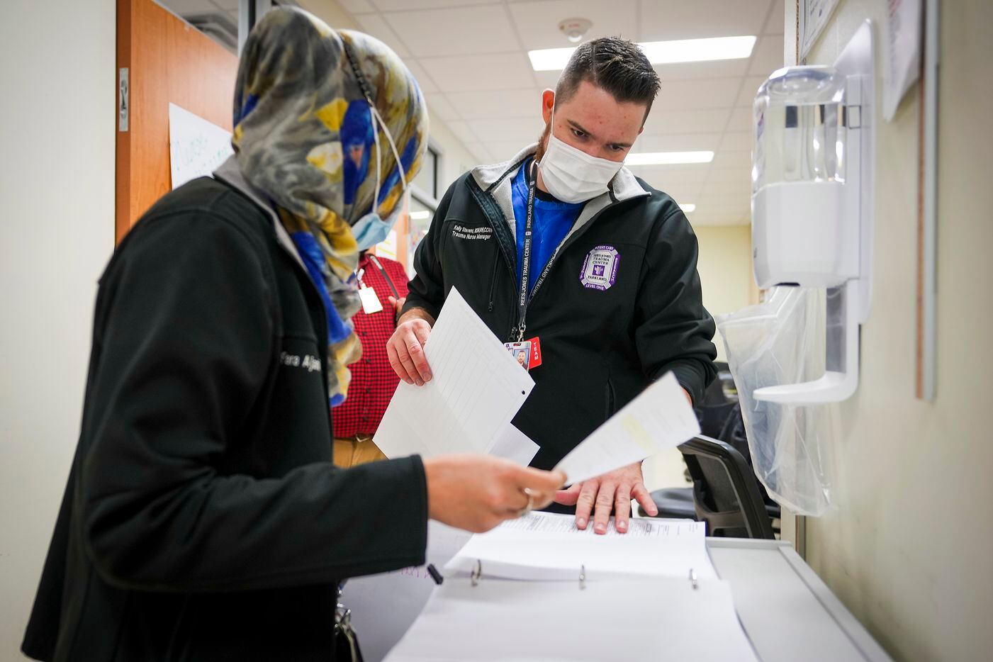 Nurses Kelly Stevens, unit manager in medicine services (right), and Fara Ajani, associate manager in medicine services, go over paperwork in the COVID-19 unit.
