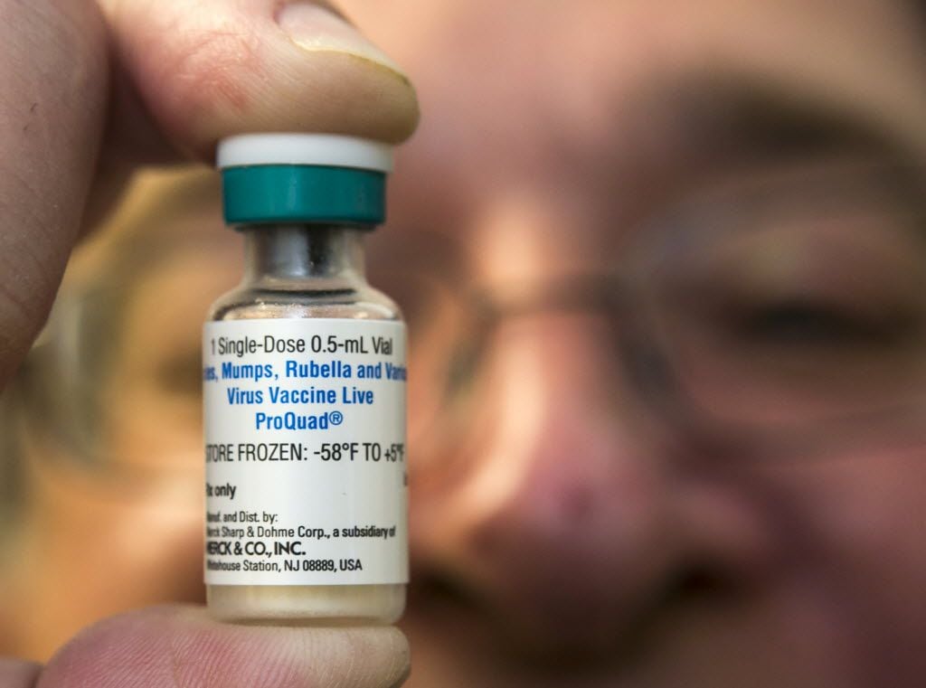 A pediatrician holds a dose of the measles-mumps-rubella (MMR) vaccine at his practice. 