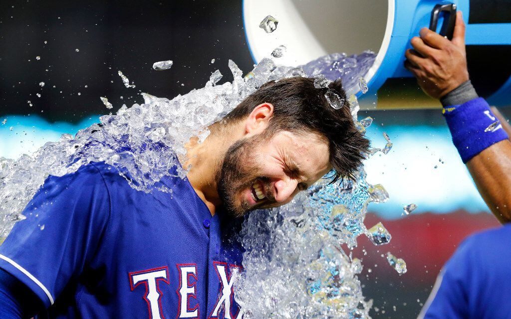 Texas Rangers left fielder Joey Gallo (13) receives the ceremonial water cooler bath room...