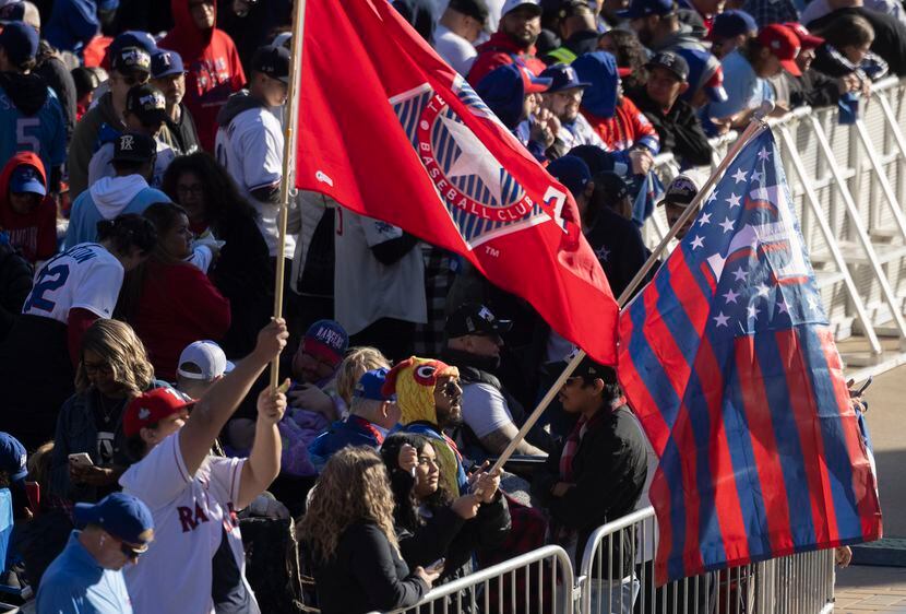 Fans wave Texas Rangers flags while waiting at the Globe Life Field’s North Plaza in...