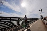 A cyclist rides across a bridge at White Rock Lake, Monday, Feb. 26, 2024, in Dallas.