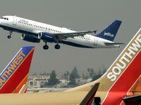 FILE - A JetBlue Airbus flies over a pair of Southwest Airlines' jets from Bob Hope Airport...
