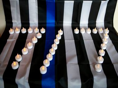Candles in the shape of the date "7/7" and a "Thin Blue Line" flag honor the fallen officers...