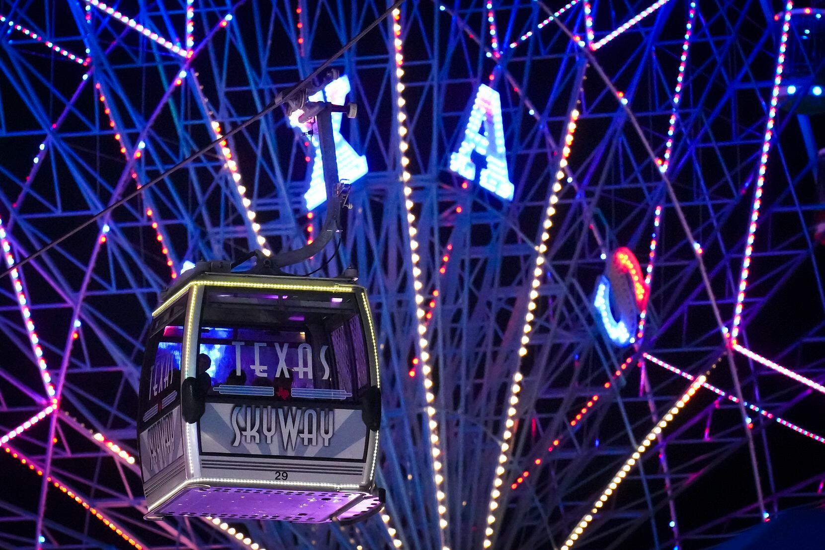 A car on the Texas Skyway passes the Texas Star ferris wheel on the midway on opening night...