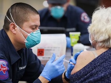 Arlington firefighter Jose Moreno administers the Moderna COVID-19 vaccine to a woman at Arlington Esports Stadium & Expo Center on Tuesday, January 5, 2021 in Arlington.  (Smiley N. Pool / The Dallas Morning News)