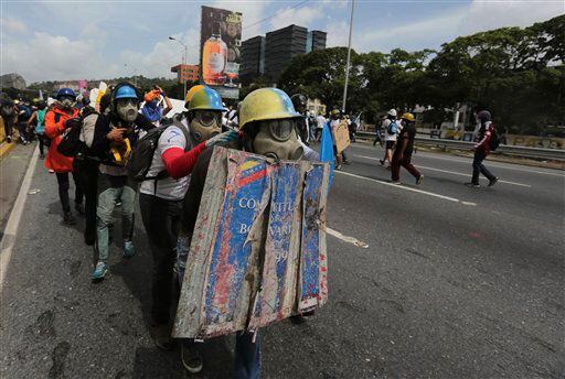 Un manifestante conduce a otros con un escudo decorado como la Constitución de Venezuela...