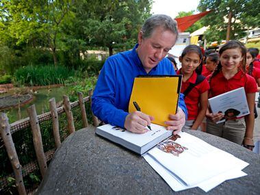 Photographer Joel Sartore (left) signs his autographs as a group of Momentous Institute...