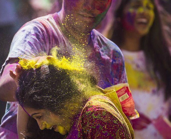 A woman is doused with colored powder during a celebration of the Hindu holiday of Holi.  