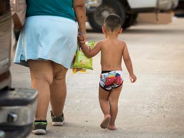 A woman walks away from Los Compadres Meat Market holding hands with a youngster on May 10,...
