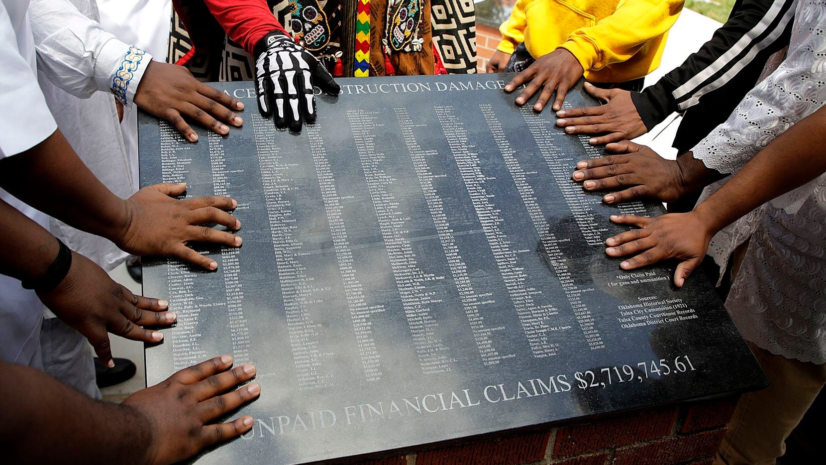 Members of the African Ancestral Society touch the 1921 Black Wall Street Memorial during...