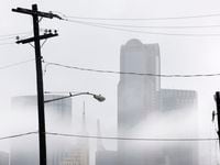 Lingering clouds and showers envelope the downtown Dallas skyline Monday afternoon, October...