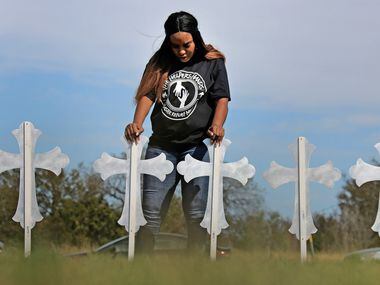 Sheree Rumph of San Antonio prays over 26 crosses placed near U.S. Highway 87 just down the...