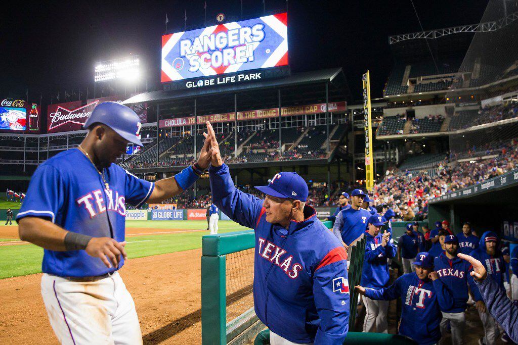 Texas Rangers shortstop Elvis Andrus gets a hand from manager Jeff Banister after scoring on...