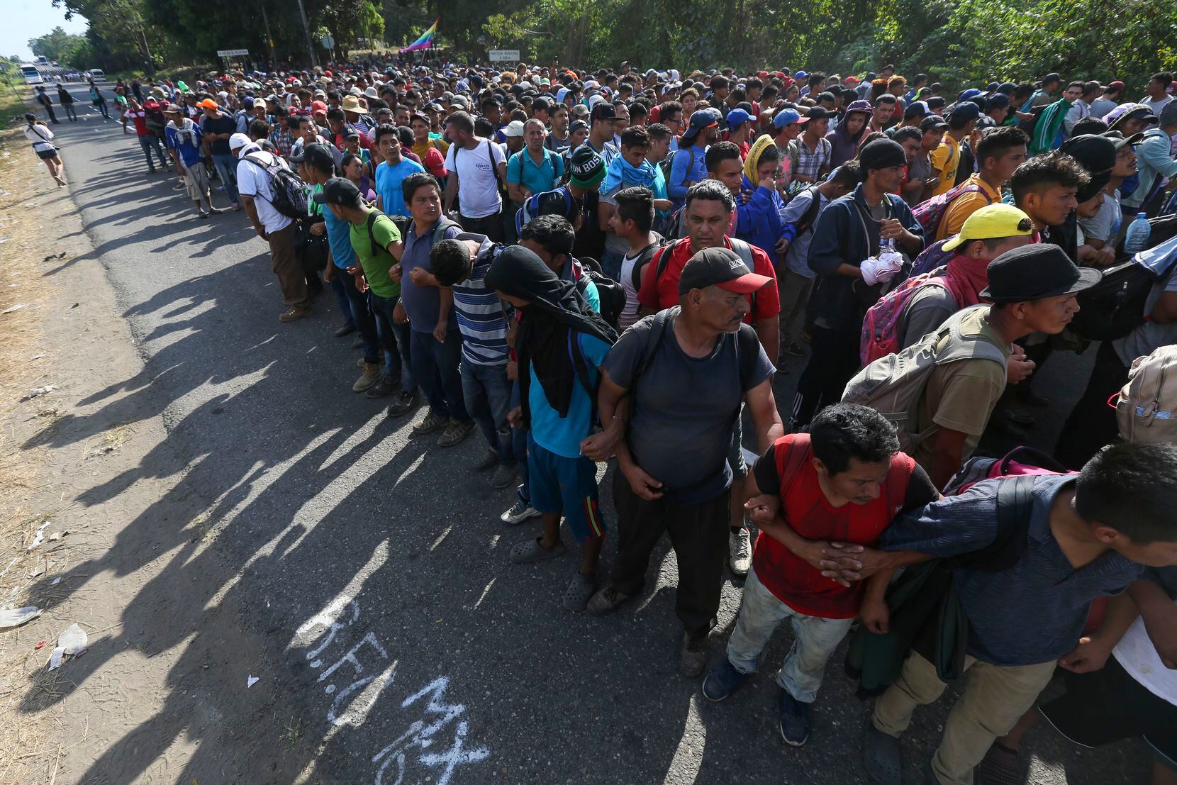 Migrants form a chain holding each other by the arms on a highway to Tapachula, Mexico, on...