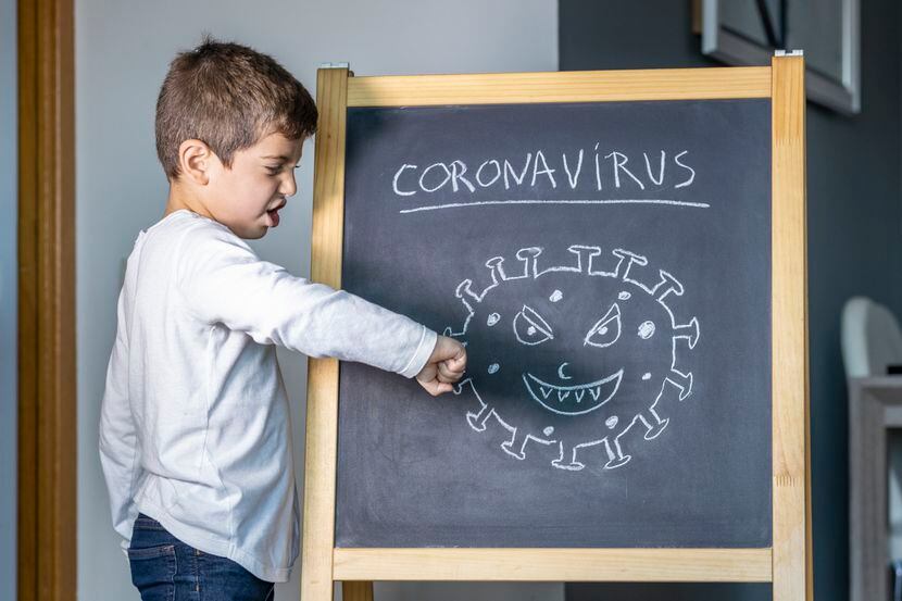 Un niño golpea con su puño un dibujo de la célula de coronavirus.