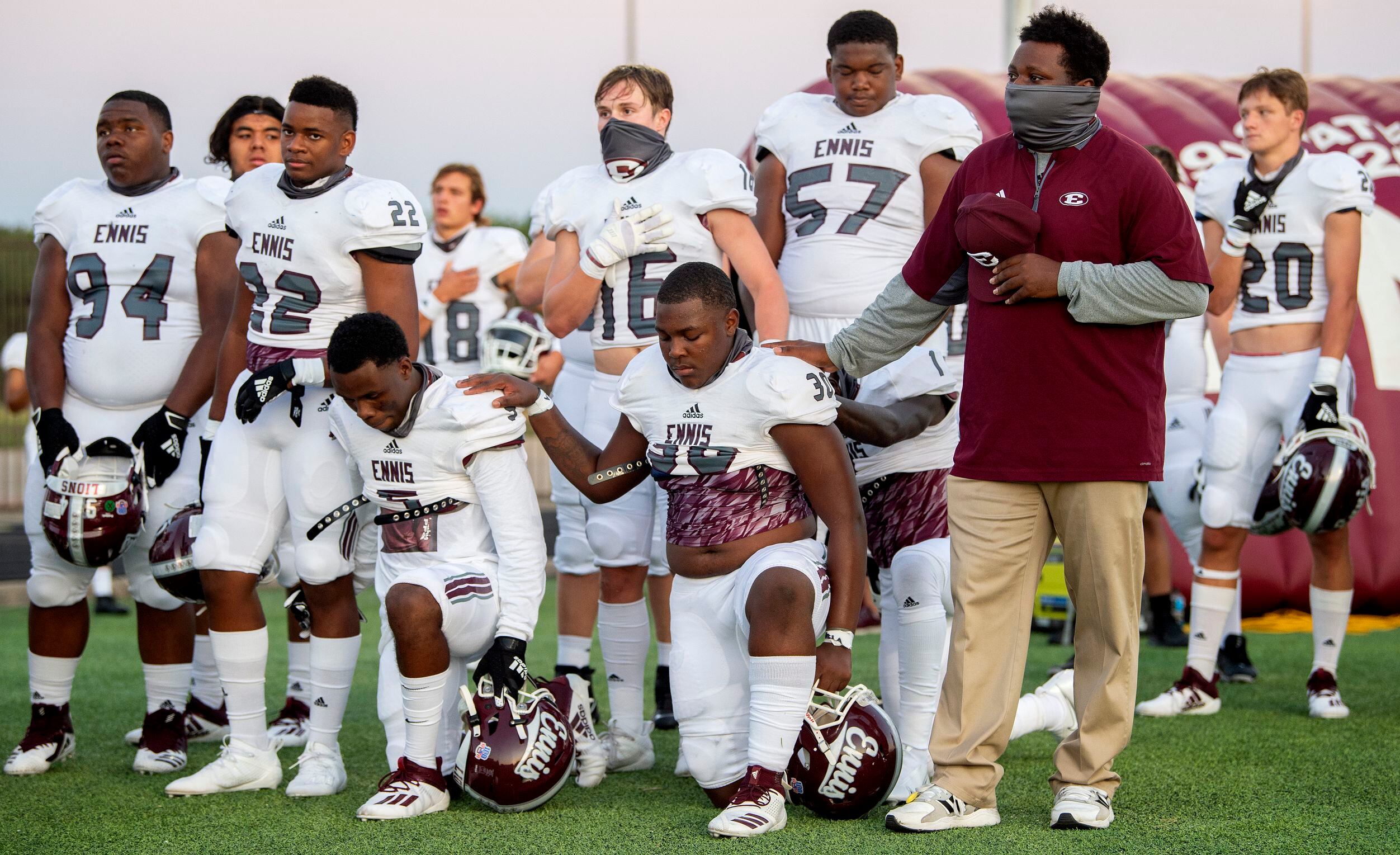 Ennis’ Stephon Townsend, left, and Ty’Quan Johnson (30) take a knee during the playing of...