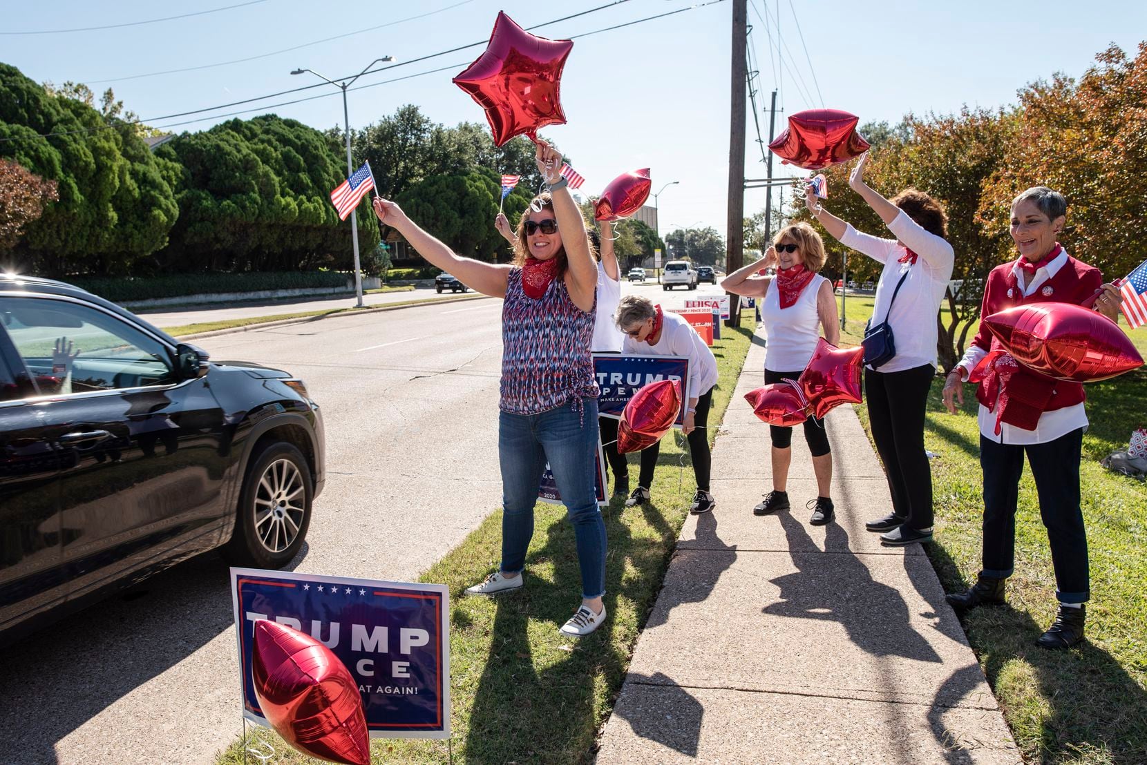 Kellie Ellington (left), along with other supporters of President Donald Trump, waved American flags Tuesday outside the Audelia Road Branch Library in Dallas while urging drivers to vote for him.