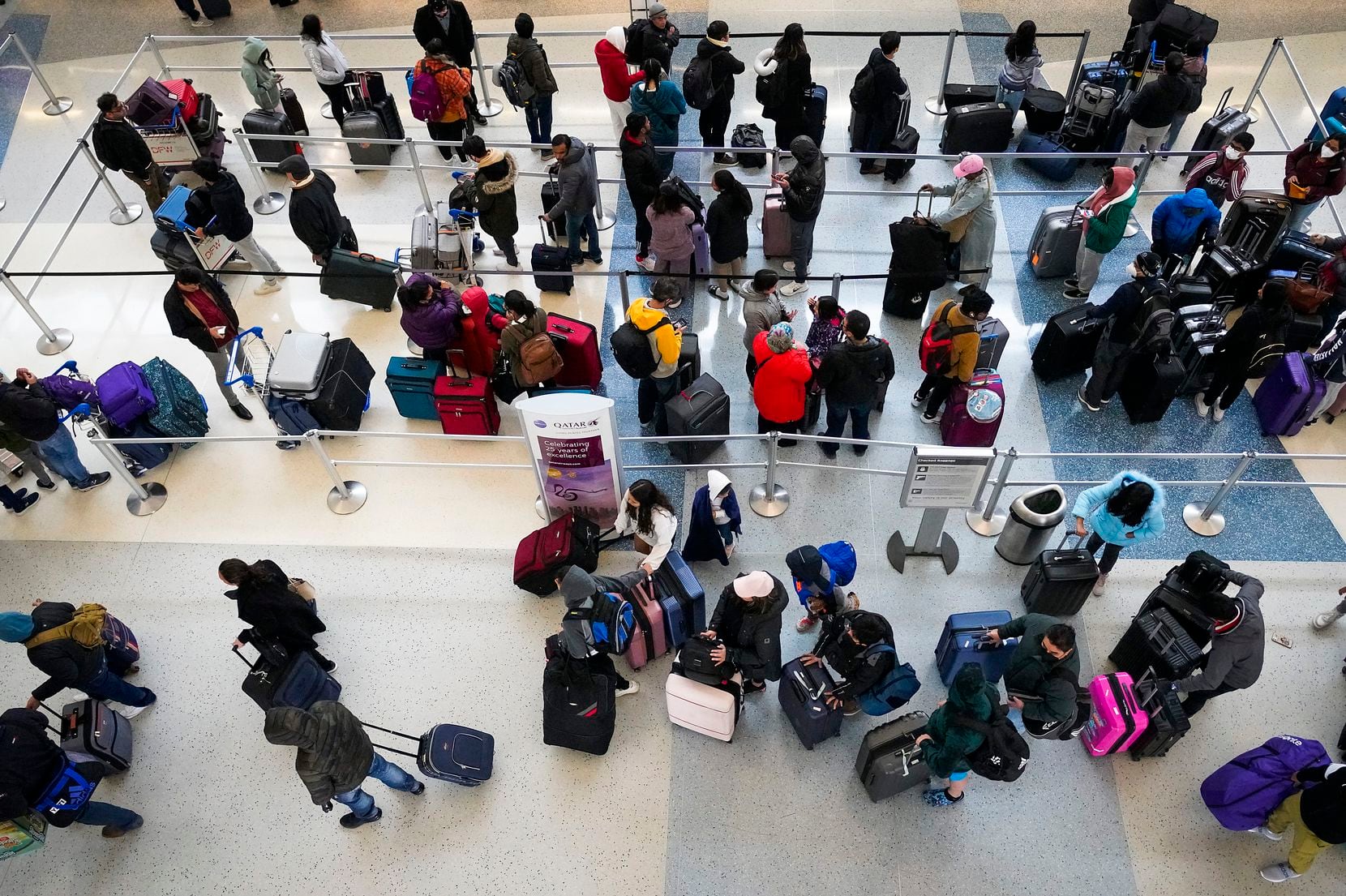 Passengers wait in a check in line for Qatar Airlines on Thursday, Dec. 22, 2022, in DFW...