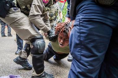 A demonstrator is restrained by police at a pro-Palestinian protest at the University of...