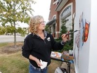 Artist Karen Cox paints a traffic signal box at Fire Station No. 1 in Grand Prairie as a sample for the Traffic Signal Box Public Art Project.