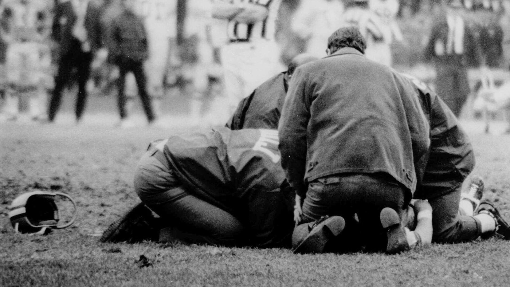 While the helmet of Chuck Hughes, Detroit Lions' wide receiver, lies near spot where he fell...