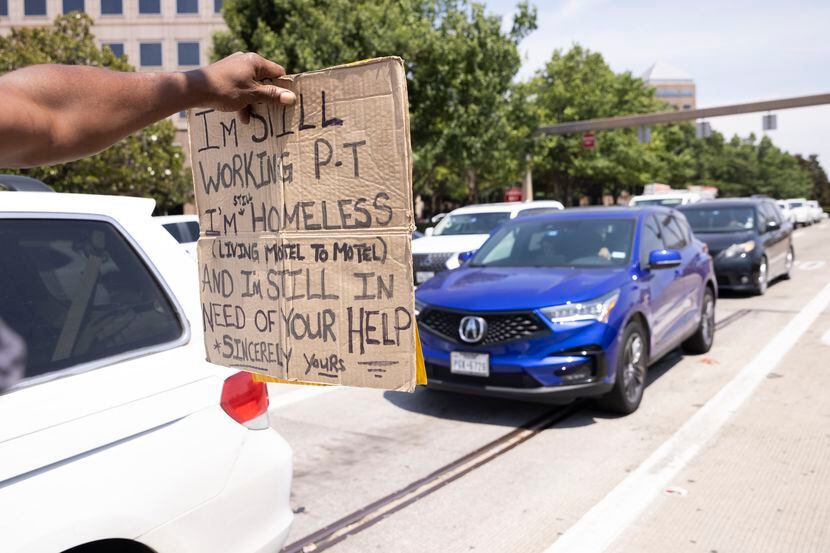A man holds out a sign while panhandling at Park Lane and North Central Expressway on...