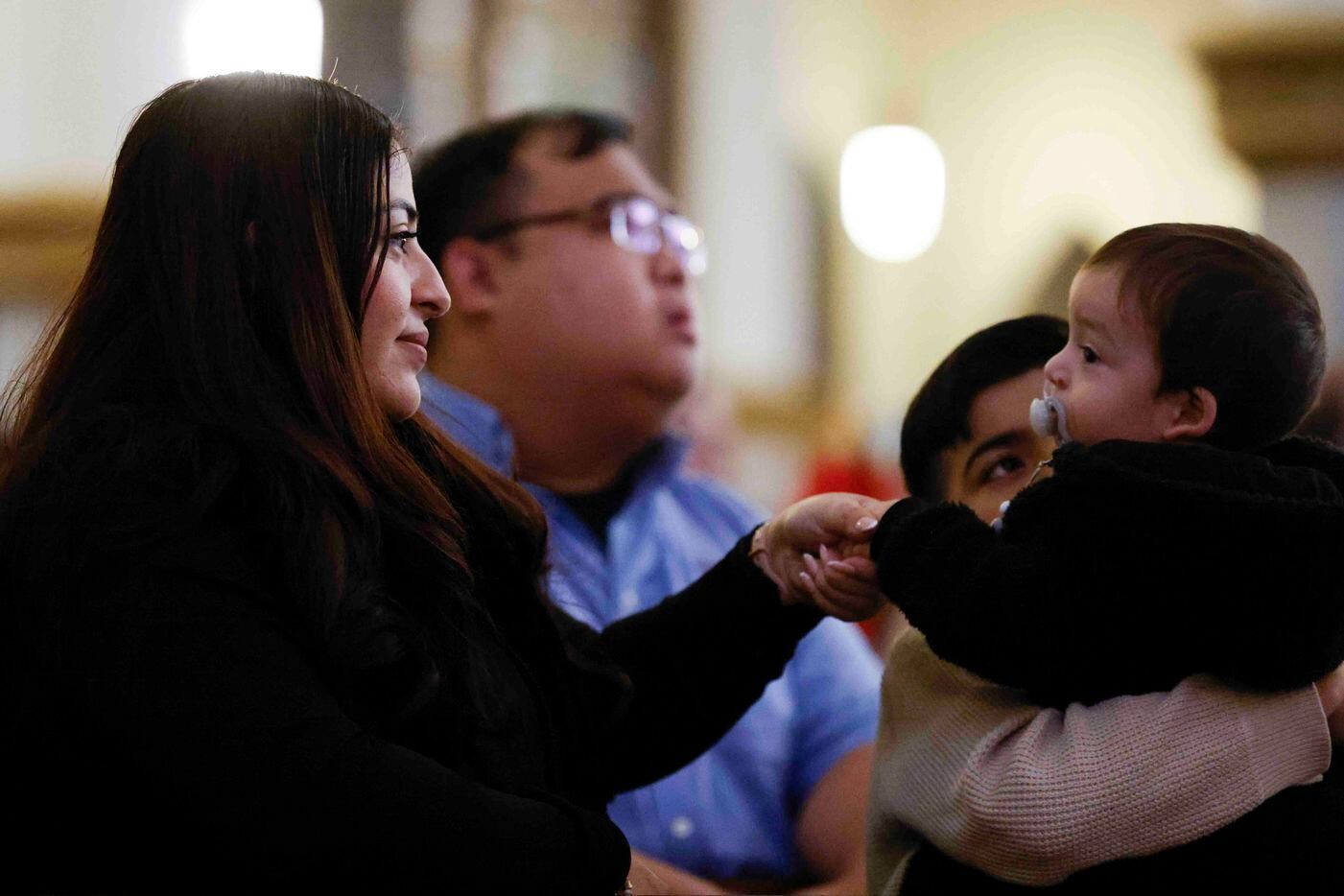 Parishioner Ana Nino, left, greets her 11-month-old son Maximiloano Nino during a memorial...