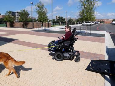 Texas A&M graduate student Kyle Cox, who has Duchenne Muscular Dystrophy, and his golden...
