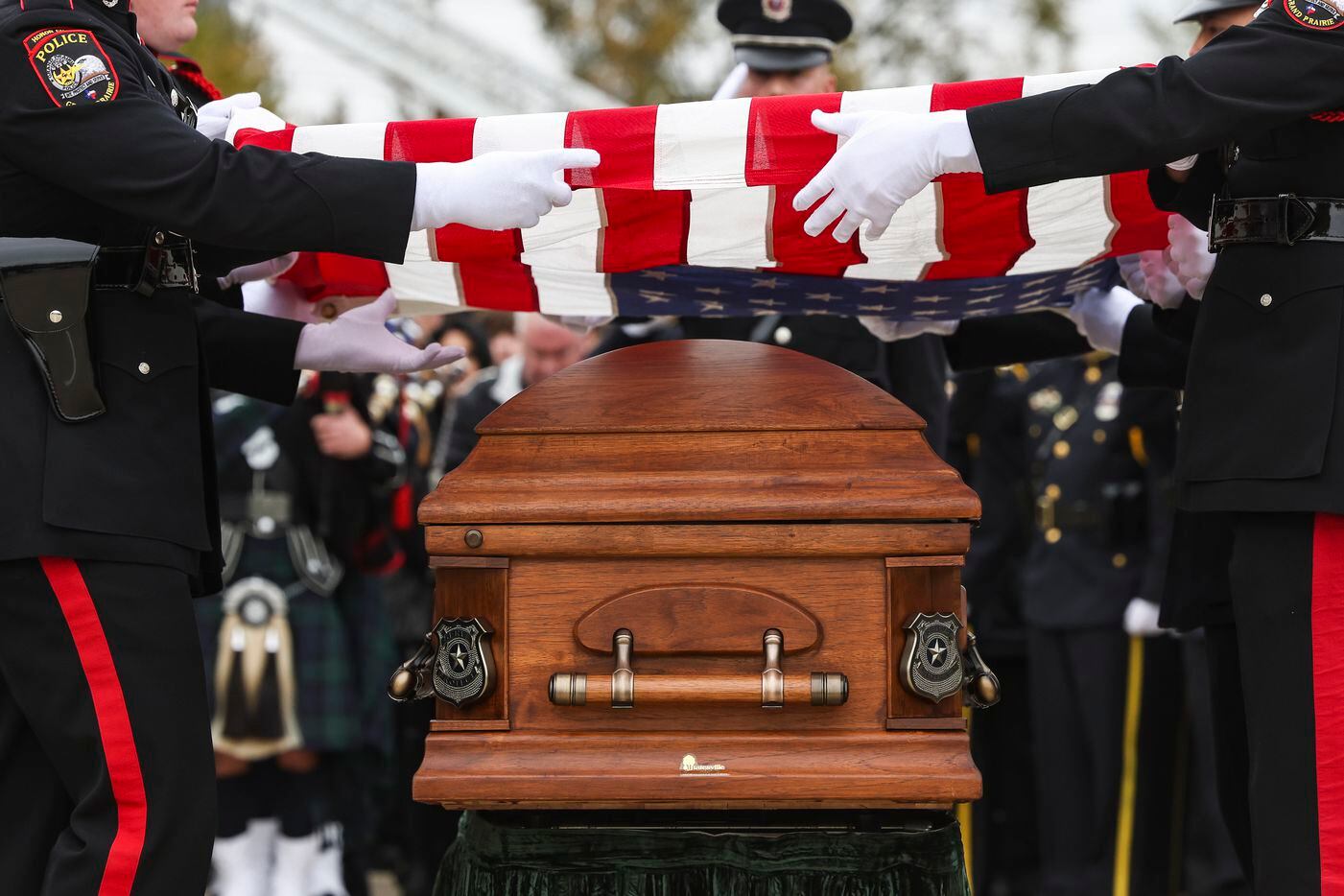The American flag is lifted by Grand Prairie Police Department Honor Guard above the casket...