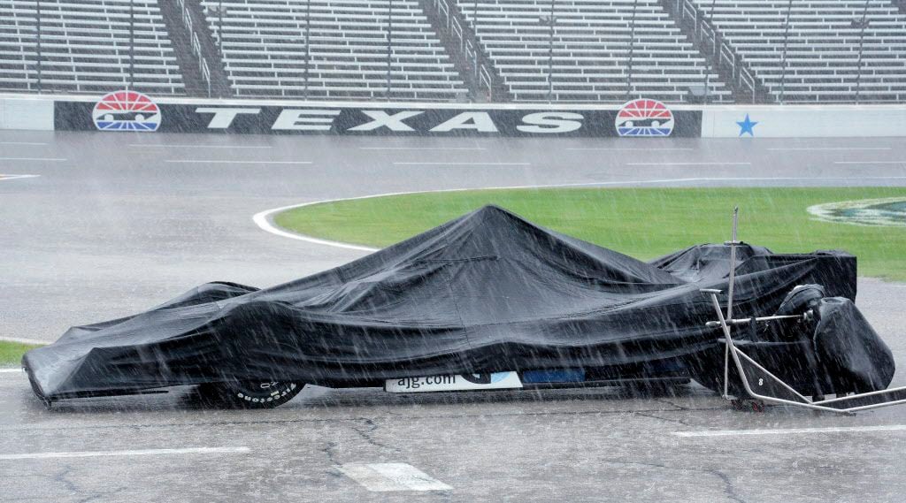 The race car of Max Chilton, from England, is covered by a tarp during a thunderstorm which...