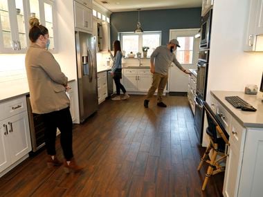 Mackenzie Larch (left), a Realtor with Ebby Halliday, looks on as Kelsey Hand (center) and her husband Steven from Champaign, Ill., check out the kitchen at an open house at 1600 Commerce Drive in Plano on Thursday.