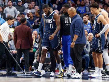 Dallas Mavericks forward Tim Hardaway Jr. (11) limps off the court after slipping on the...