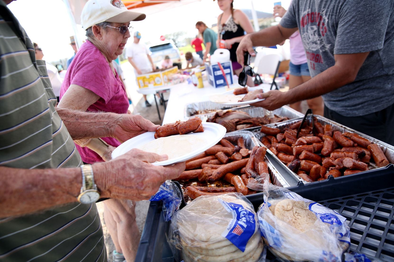 Gene Lynch and his wife Jo Lynch of Lockport are served barbecue by volunteers from Austin...