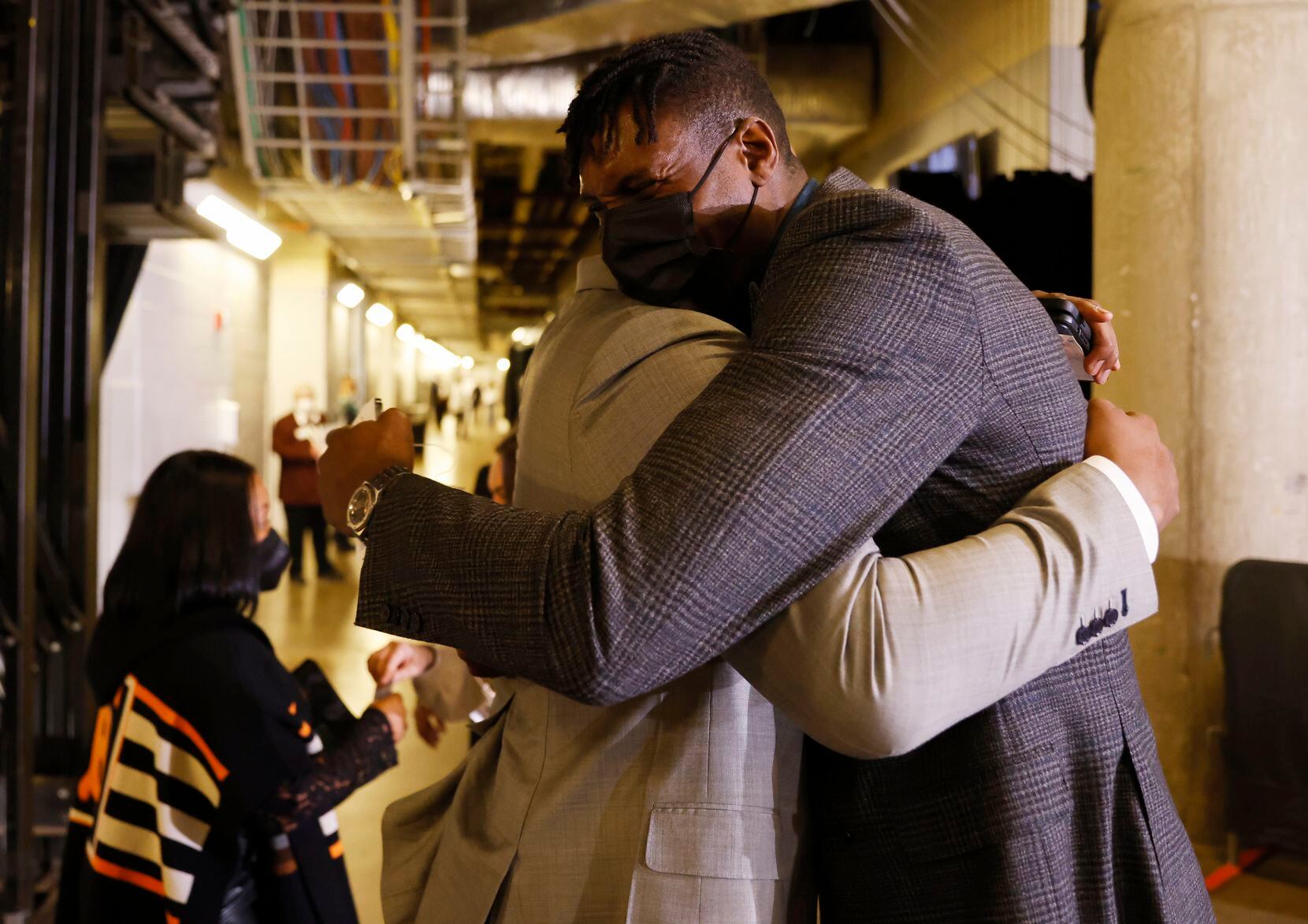 Former Dallas Mavericks players Caron Butler  and Ian Mahinmi hug before a game between the...