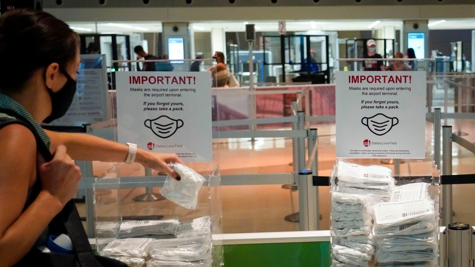 A passenger grabs a free mask before entering the security checkpoint at Dallas Love Field.